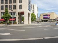 people cross an intersection near tall buildings on a busy street in a city in europe