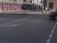 the traffic light turns at a busy street corner in europe by an old building with pink painted signs on it