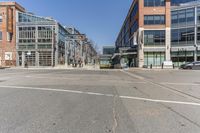 a street with vehicles parked in front of tall buildings in the background is a large brick building