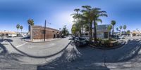 a fish eye view of a busy street with palm trees and a building in the background