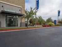 a paved street outside a business with cars and flags in the foregrounded photo