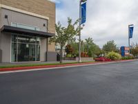 a paved street outside a business with cars and flags in the foregrounded photo