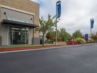 a paved street outside a business with cars and flags in the foregrounded photo