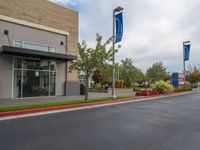 a paved street outside a business with cars and flags in the foregrounded photo