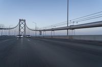 a view of traffic driving on a freeway over an arch of a bridge across the river