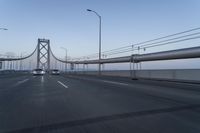 a view of traffic driving on a freeway over an arch of a bridge across the river