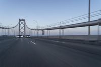 a view of traffic driving on a freeway over an arch of a bridge across the river