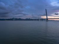 a large bridge spanning over a river under a blue sky during sunset or at night