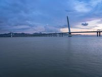 a large bridge spanning over a river under a blue sky during sunset or at night