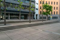 a city street lined with steps and trees along with some buildings behind it that has a few people in front of it