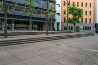 a city street lined with steps and trees along with some buildings behind it that has a few people in front of it