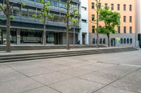 a city street lined with steps and trees along with some buildings behind it that has a few people in front of it