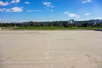 empty parking lot with trees and buildings in the background under blue skies with white clouds