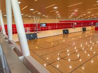 basketball court with wooden flooring and red tiles on the walls and ceiling, with fans on the roof