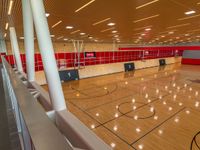 basketball court with wooden flooring and red tiles on the walls and ceiling, with fans on the roof