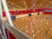 basketball court with wooden flooring and red tiles on the walls and ceiling, with fans on the roof