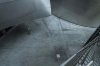 an aerial view of a man walking down stairs next to a building, surrounded by stairs