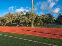 a red running track going in different directions and numbers on it that is next to a tall structure