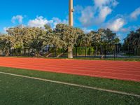 a red running track going in different directions and numbers on it that is next to a tall structure