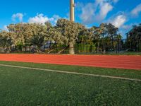 a red running track going in different directions and numbers on it that is next to a tall structure