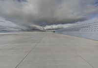 a plane sits on a runway with several barbed wire to the side of it and mountains in the distance