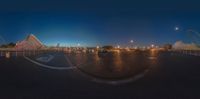 a view through the fisheye lens of an amusement park at night with the sky in the background