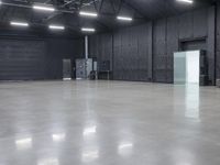 a empty industrial building with large gray floors and a white freezer and refrigerator in front of door