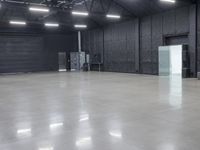 a empty industrial building with large gray floors and a white freezer and refrigerator in front of door