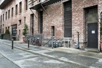 an old brick building with a bicycle on the sidewalk and some steps and bars on the front door