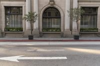 there is a white arrow painted on the street corner in front of the building to indicate where the intersection of two directions