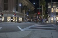 a night time scene of an intersection with traffic lights and pedestrians crossing it in the background