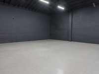 a empty room with concrete floor in it, on the corner is a bright white light