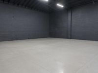 a empty room with concrete floor in it, on the corner is a bright white light