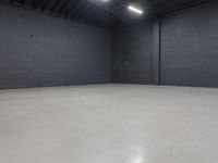 a empty room with concrete floor in it, on the corner is a bright white light