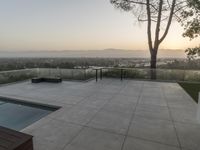 the patio overlooks the city and hills at sunset, with a large plunge on it