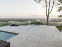 the patio overlooks the city and hills at sunset, with a large plunge on it