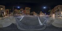 360 - zoom photo at night shows an empty city street lined with high rise buildings