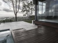 a view of a large deck with a hot tub and glass wall overlooking trees and water