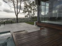 a view of a large deck with a hot tub and glass wall overlooking trees and water