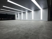 a large parking garage with lights that are attached to the ceiling and concrete flooring