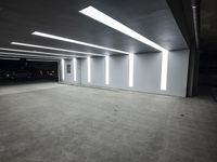 a large parking garage with lights that are attached to the ceiling and concrete flooring