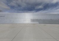 the view of a concrete wall with razors above it and a sky with clouds