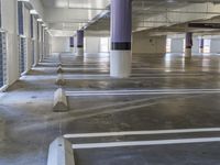 the view inside of a parking garage showing empty white areas and yellow poles in front