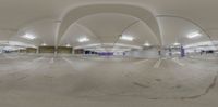 an empty parking garage with curved ceiling columns and an overhead ceiling mirror in the foreground