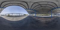 a fisheye lens photo looking at an open parking garage in front of a skateboard ramp