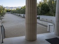 the view out an open doorway on to a large courtyard with trees and a mountain in the background