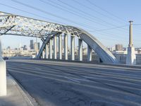 the side of a street under a bridge in a city area, with power lines crossing the road
