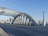 the side of a street under a bridge in a city area, with power lines crossing the road
