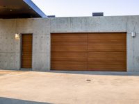 two wooden garage doors on concrete wall of house with open space in front of door