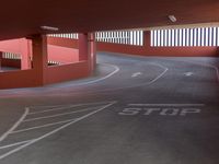 a large parking garage with graffiti on the floor and on the road, stop and go